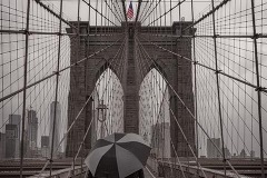 Two lovers stroll across the Brooklyn Bridge on a rainy morning in New York City